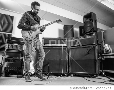 Practicing his electric guitar in a jam room 23535763