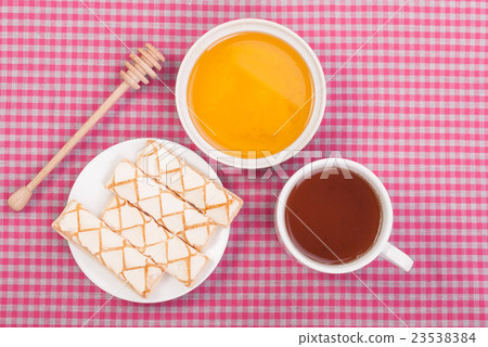 Tea biscuits and honey on the tablecloth. Tea biscuits and honey on the tablecloth. 23538384