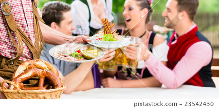 Waiter serving food in Bavarian beer garden 23542430