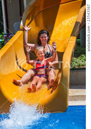 Happy family with child on water slide at aquapark Happy family with child on water slide at aquapark 23543567
