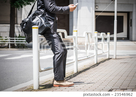 Businessman looking at a smartphone outdoors Businessman looking at a smartphone outdoors 23546962