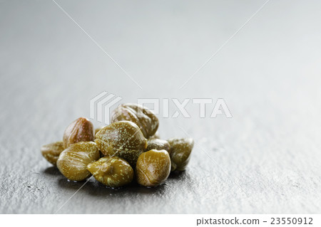 marinated capers in olive bowl on slate board 23550912