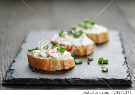 crunchy baguette slices with cream cheese and green onion on slate board 23551371