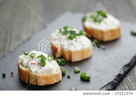 crunchy baguette slices with cream cheese and green onion on slate board 23551374
