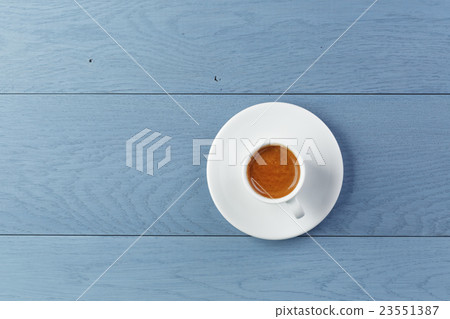 cup of fresh espresso on vintage blue table from above 23551387