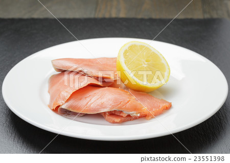 rolls of sliced smoked salmon on slate board 23551398