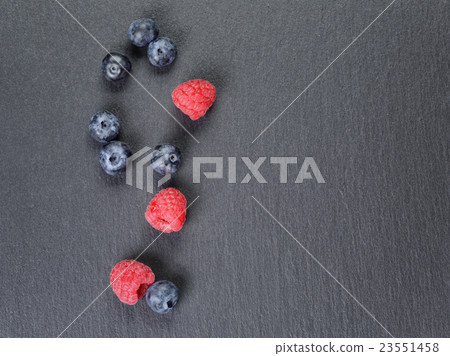 blueberries and raspberries on slate surface 23551458