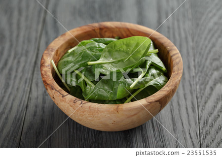 fresh spinach leaves in olive bowl on wood table 23551535