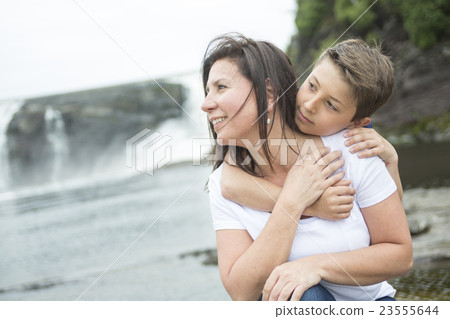 mother and son playing in front of a waterfall mother and son playing in front of a waterfall 23555644