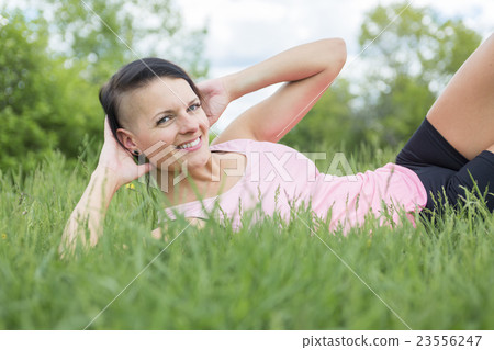 Young female athlete excercising and stretching in 23556247
