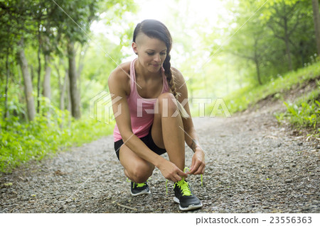 sporty woman running outdoors in park 23556363