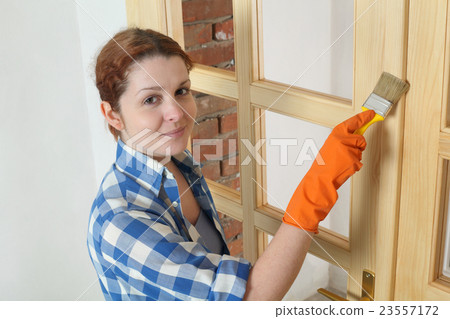 Young girl worker, painting new wooden door 23557172