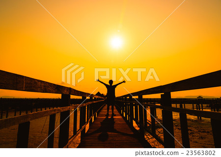Happy free man silhouette on wooden bridge Happy free man silhouette on wooden bridge 23563802