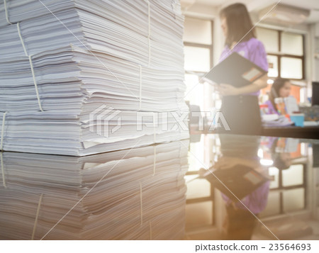Pile of unfinished documents on office desk 23564693