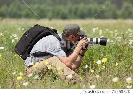 Photographer is taking a picture on green meadow Photographer is taking a picture on green meadow 23568798