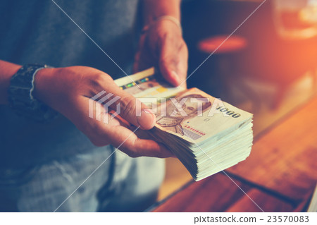 Hands counting Thai Baht bills. Toned picture Hands counting Thai Baht bills. Toned picture 23570083