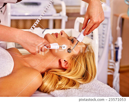 Young woman receiving electric facial massage. Young woman receiving electric facial massage. 23571053