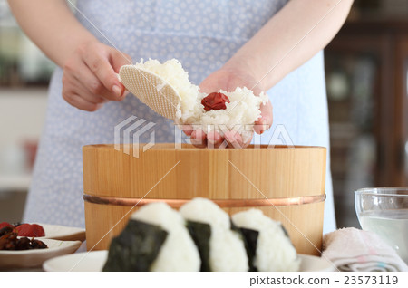 A woman putting umeboshi in onigiri 23573119