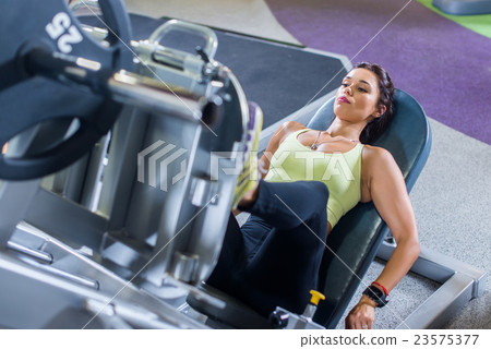 Fit woman working out on leg press machine in gym. 23575377