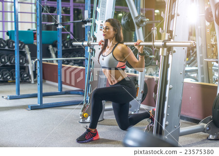 Fit girl doing lunges with the smith machine 23575380