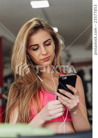 Blonde with a phone  at the gym. Listening to 23577853