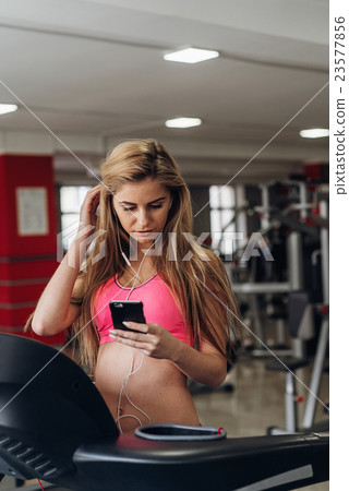 Blonde with a phone  at the gym. Listening to 23577856