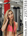 Blonde with a phone  at the gym. Listening to 23577858