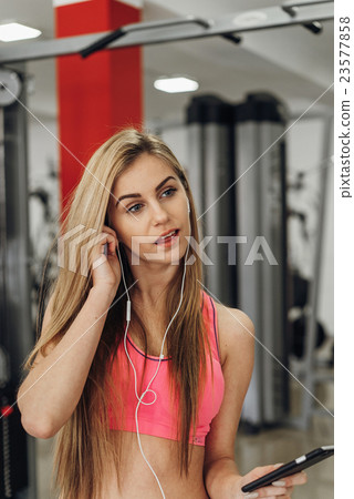Blonde with a phone  at the gym. Listening to 23577858