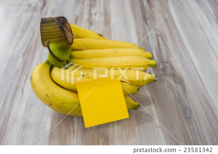 Banana with Sticky Note on wood table . Banana with Sticky Note on wood table . 23581342