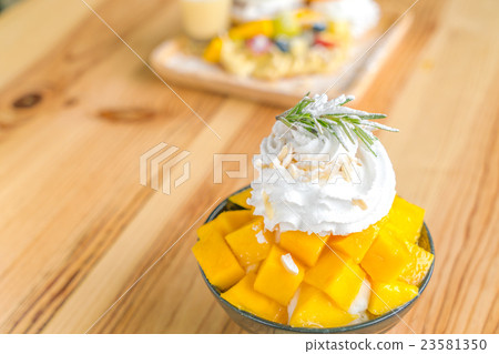 Korean style fresh mango shaved ice on wood table . 23581350