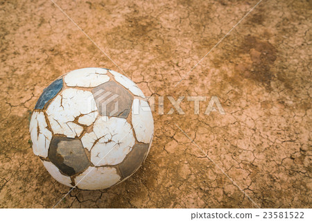Old soccer ball on Dry and cracked ground texture . 23581522