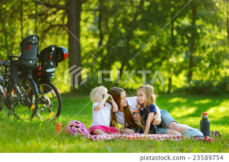 Young mother and her daughters picnicking 23589754