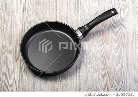 Frying pan on wooden table Frying pan on wooden table 23597533