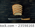 Sliced bread and knife on black wooden table 23598168
