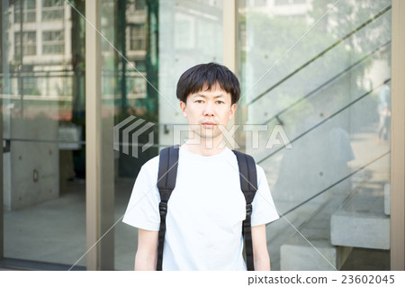 A man with a serious look standing in front of a building A man with a serious look standing in front of a building 23602045