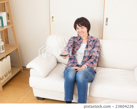 A woman watching TV with a remote control A woman watching TV with a remote control 23604226