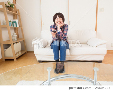 一個女人用遙控器看電視 23604227