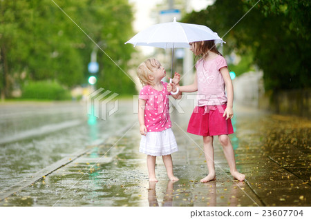 Two cute little sisters having fun under a rain 23607704