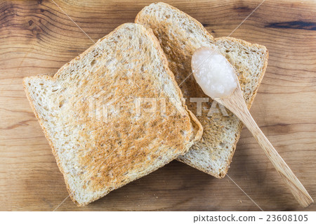 Brown whole wheat toast with white jam on spoon Brown whole wheat toast with white jam on spoon 23608105