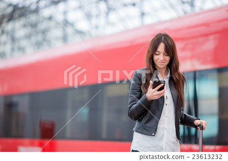 Young woman with luggage looking oh cellphone at a Young woman with luggage looking oh cellphone at a 23613232