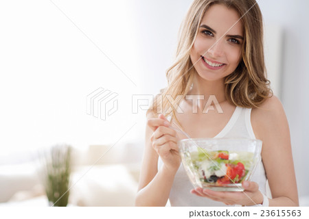 Cheerful woman eating vegetable salad. Cheerful woman eating vegetable salad. 23615563