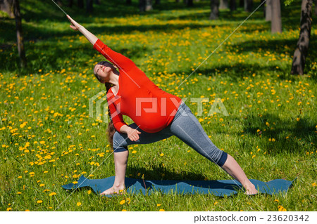Pregnant woman doing asana Utthita parsvakonasana 23620342