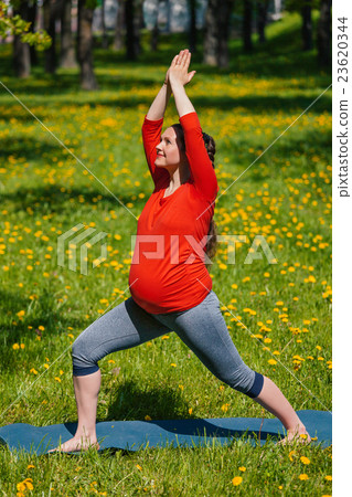 Pregnant woman doing asana Virabhadrasana outdoors 23620344