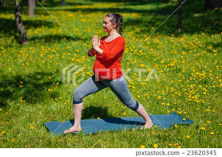 Pregnant woman doing asana Virabhadrasana outdoors Pregnant woman doing asana Virabhadrasana outdoors 23620345