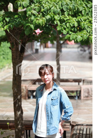 A young Japanese woman standing in a park in the city A young Japanese woman standing in a park in the city 23622885