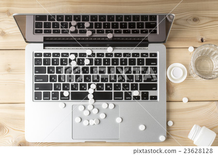 Heap of round white pills on the open laptop Heap of round white pills on the open laptop 23628128