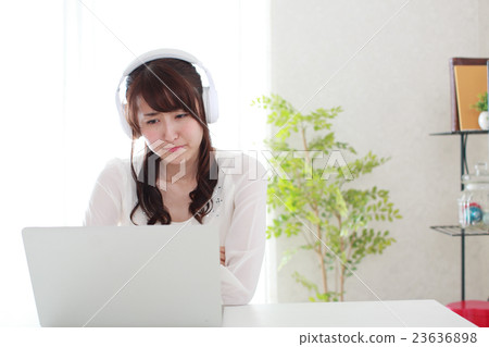 A young woman wearing headphones and doing a personal computer 23636898