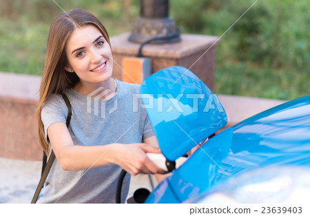 Woman charging battery of hybrid car 23639403