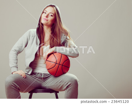 Sporty teen girl in hood holding basketball. 23645120
