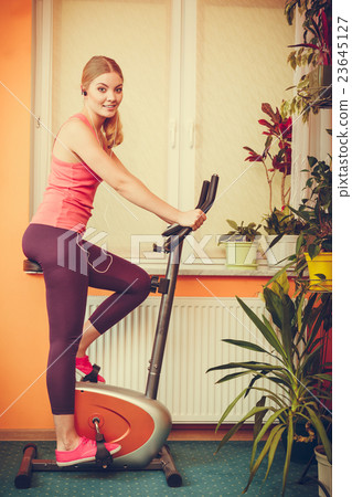 Woman on exercise bike listening music. Fitness Woman on exercise bike listening music. Fitness 23645127